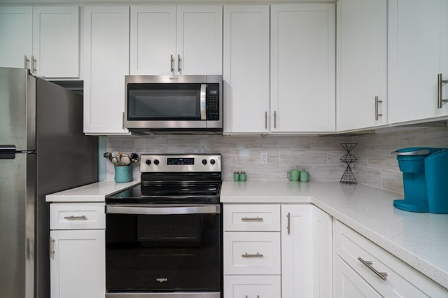 kitchen with tasteful backsplash, light stone countertops, white cabinets, and appliances with stainless steel finishes