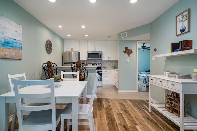 kitchen featuring light hardwood / wood-style flooring, appliances with stainless steel finishes, ceiling fan, decorative backsplash, and white cabinets