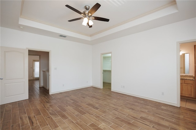 unfurnished room with ornamental molding, hardwood / wood-style flooring, a raised ceiling, and ceiling fan