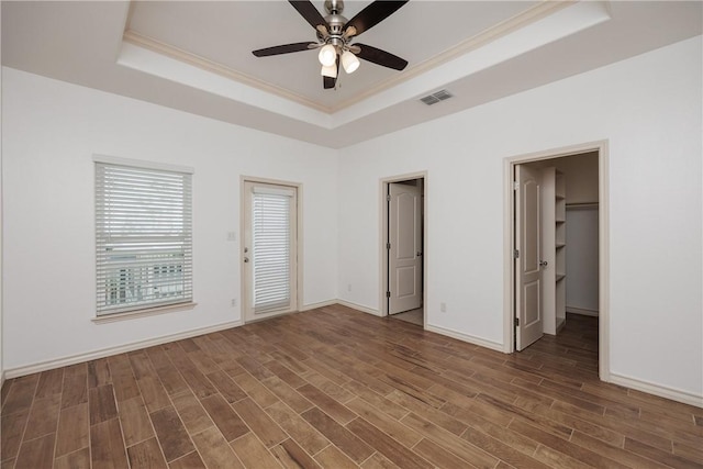 14202 Encantada Ave Unit 603, Corpus Christi, TX 78418 - unfurnished bedroom featuring a tray ceiling, wood finished floors, ornamental molding, baseboards, and a spacious closet
