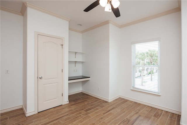 unfurnished bedroom featuring ornamental molding, light hardwood / wood-style floors, ceiling fan, and built in desk