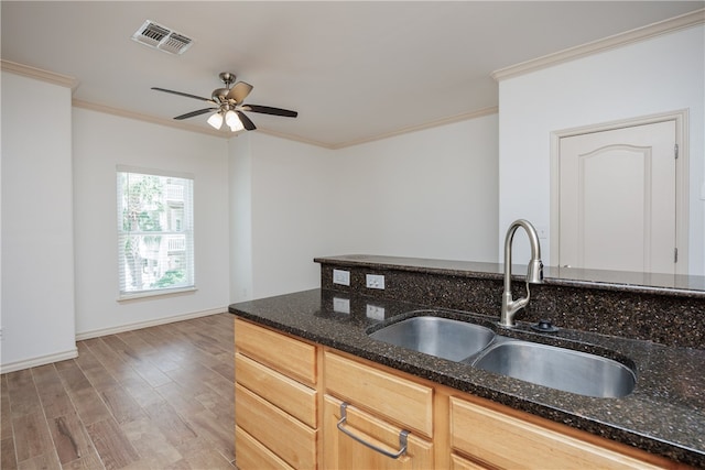 kitchen with dark stone counters, hardwood / wood-style flooring, sink, crown molding, and light brown cabinets