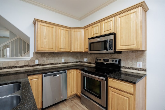 kitchen with crown molding, stainless steel appliances, dark stone counters, and light brown cabinetry