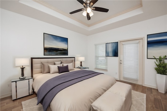 bedroom featuring ornamental molding, a tray ceiling, ceiling fan, and light hardwood / wood-style flooring