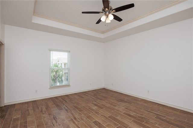 empty room with dark hardwood / wood-style flooring, a tray ceiling, ceiling fan, and crown molding