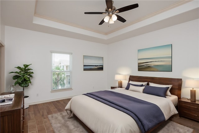 bedroom with ornamental molding, dark hardwood / wood-style flooring, ceiling fan, and a raised ceiling