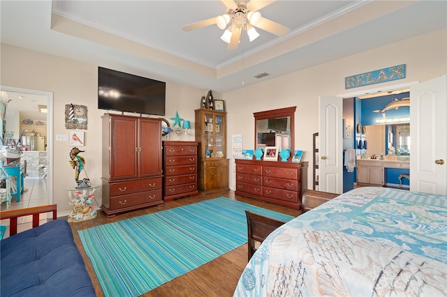 bedroom featuring ensuite bathroom, dark hardwood / wood-style flooring, ceiling fan, and a raised ceiling