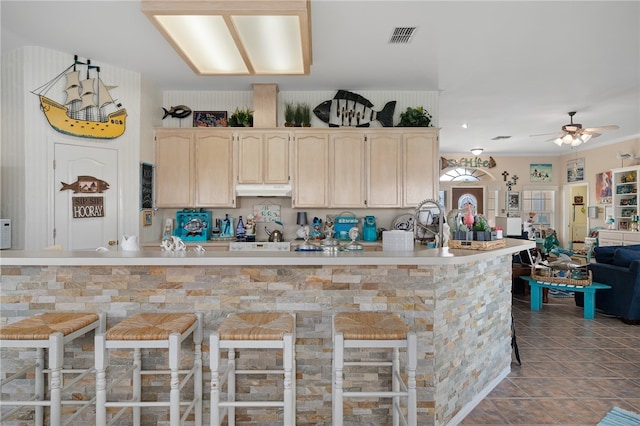 kitchen with ceiling fan, light brown cabinets, tile patterned flooring, and a breakfast bar