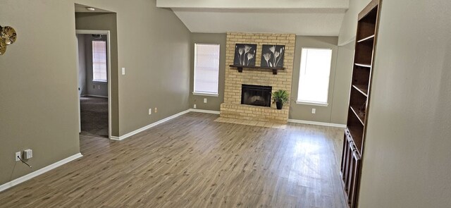 unfurnished living room with a fireplace, wood-type flooring, and a healthy amount of sunlight