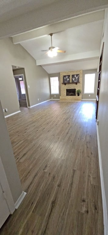 unfurnished living room featuring lofted ceiling with beams, hardwood / wood-style flooring, ceiling fan, and a fireplace