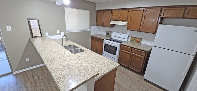 kitchen with white appliances, light stone countertops, sink, hardwood / wood-style flooring, and kitchen peninsula