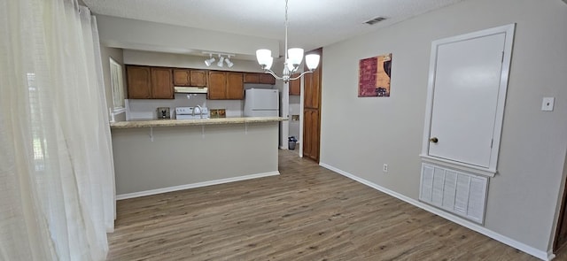 kitchen with a notable chandelier, white appliances, dark hardwood / wood-style flooring, hanging light fixtures, and kitchen peninsula