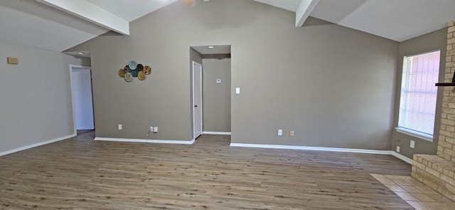 empty room with lofted ceiling with beams, a wealth of natural light, and hardwood / wood-style floors