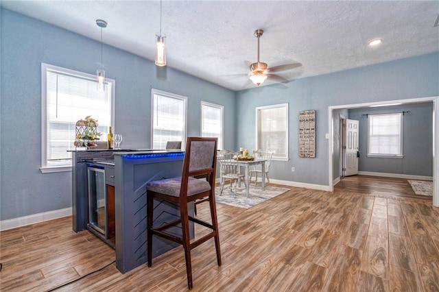 10634 Veda Dr, Corpus Christi, TX 78410 - kitchen with wood finished floors, a ceiling fan, a breakfast bar, blue cabinetry, and pendant lighting