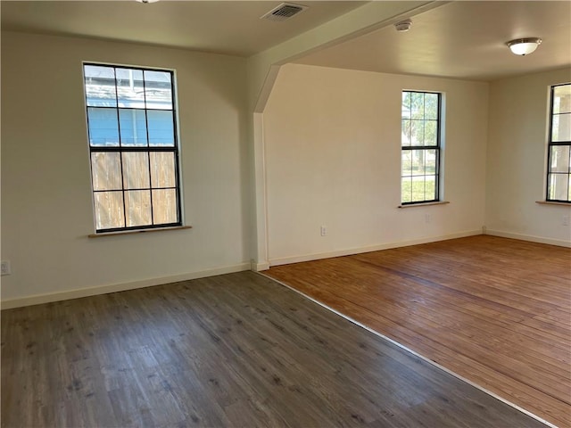 spare room featuring visible vents, baseboards, and wood finished floors