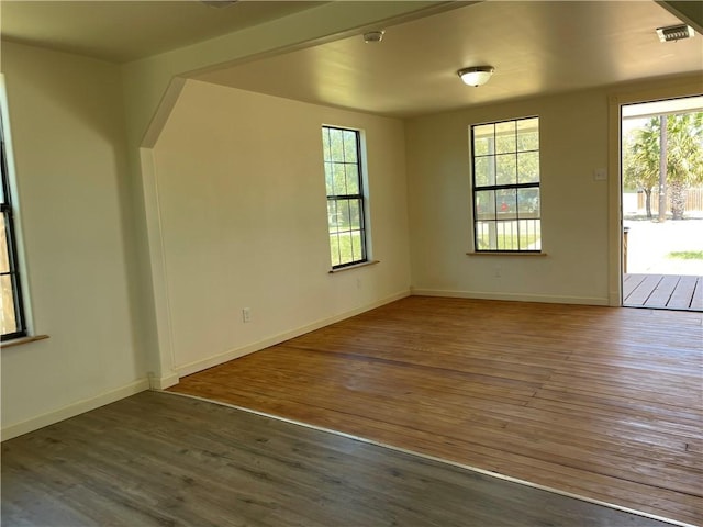 empty room featuring hardwood / wood-style flooring, visible vents, and baseboards