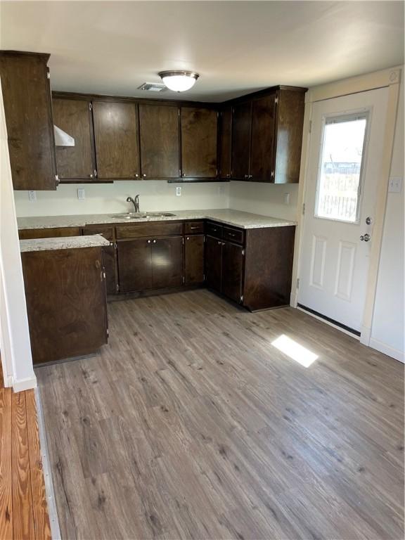 kitchen with visible vents, a sink, light wood-style floors, light countertops, and dark brown cabinets