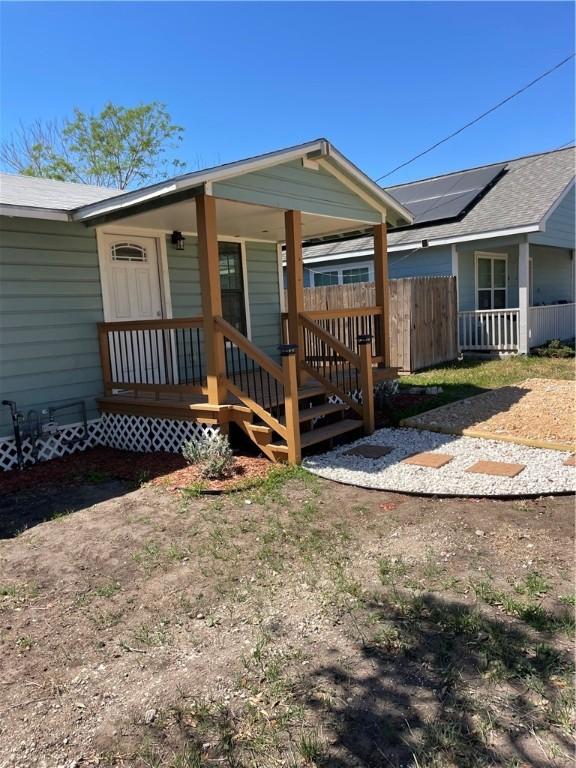 back of property featuring covered porch and fence