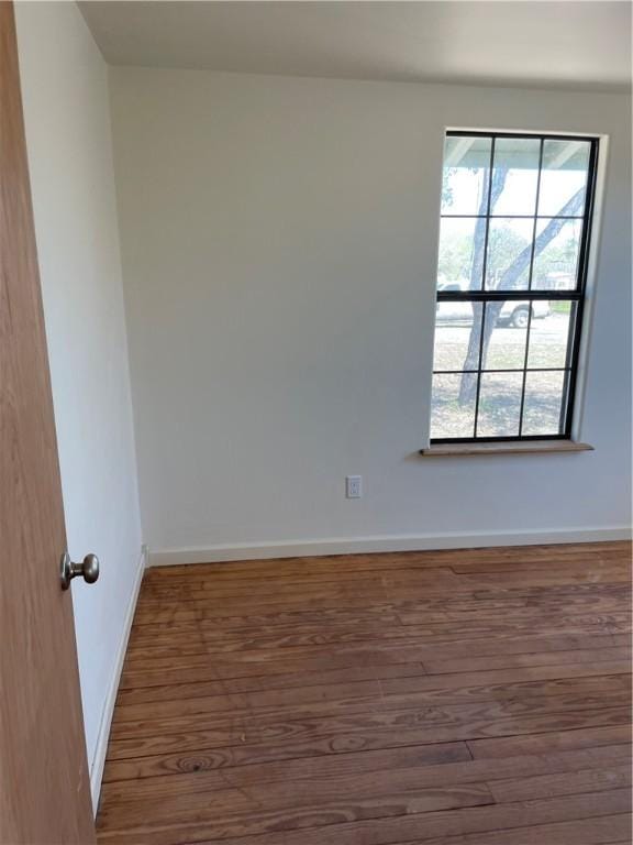 unfurnished room with baseboards and wood finished floors