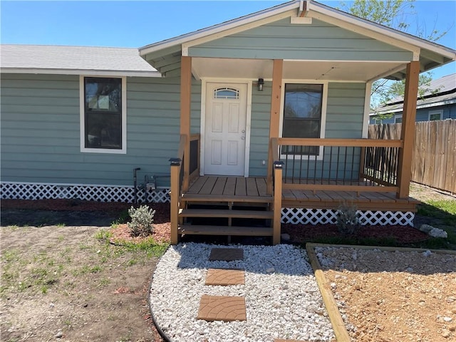 view of exterior entry with a porch and fence