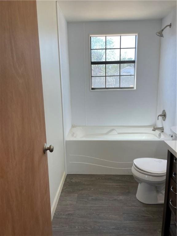 bathroom with vanity, toilet, wood finished floors, and  shower combination