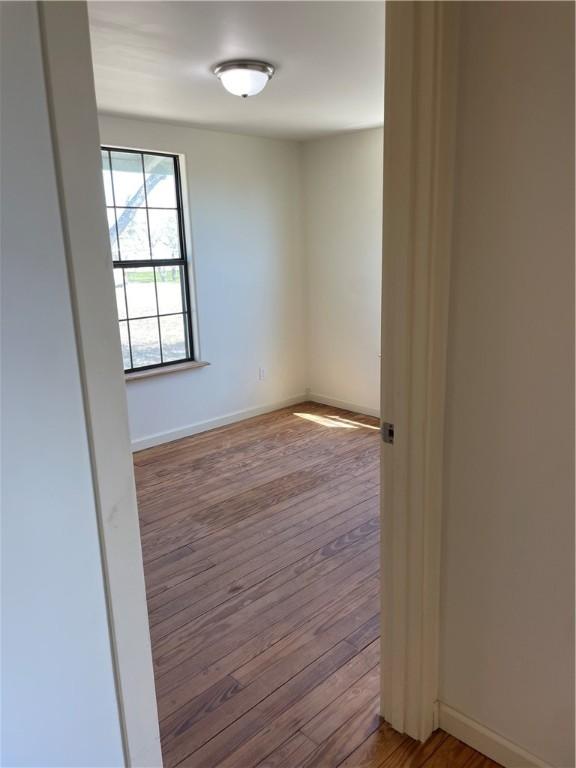 unfurnished room with baseboards and hardwood / wood-style flooring