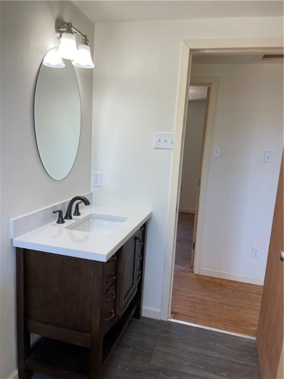 bathroom featuring vanity, baseboards, and wood finished floors