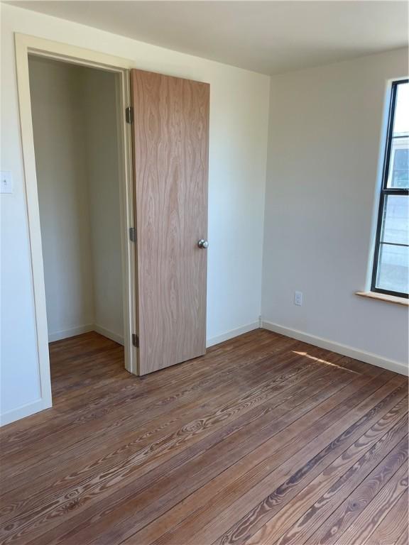 unfurnished bedroom featuring wood finished floors and baseboards