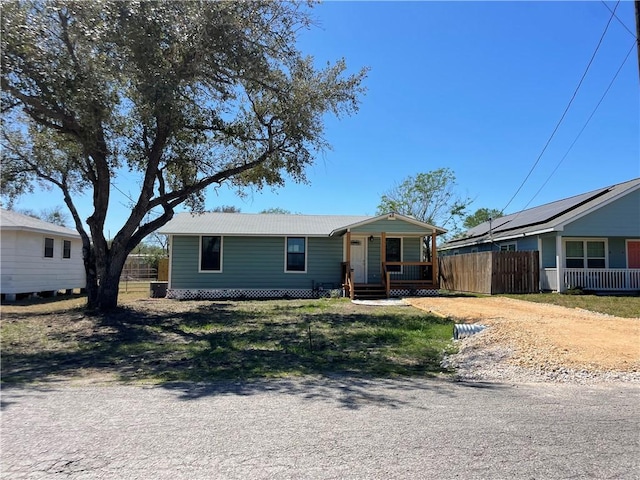 view of front of home with metal roof, covered porch, and fence