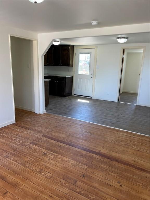 interior space with baseboards, open floor plan, and wood finished floors