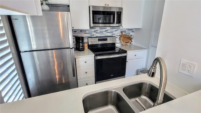 kitchen featuring tasteful backsplash, white cabinetry, appliances with stainless steel finishes, and sink