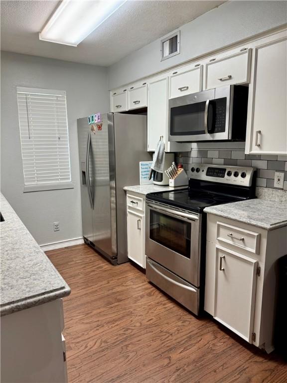 11614 Coleta Creek Dr, Corpus Christi, TX 78410 - kitchen with appliances with stainless steel finishes, light countertops, wood finished floors, and decorative backsplash