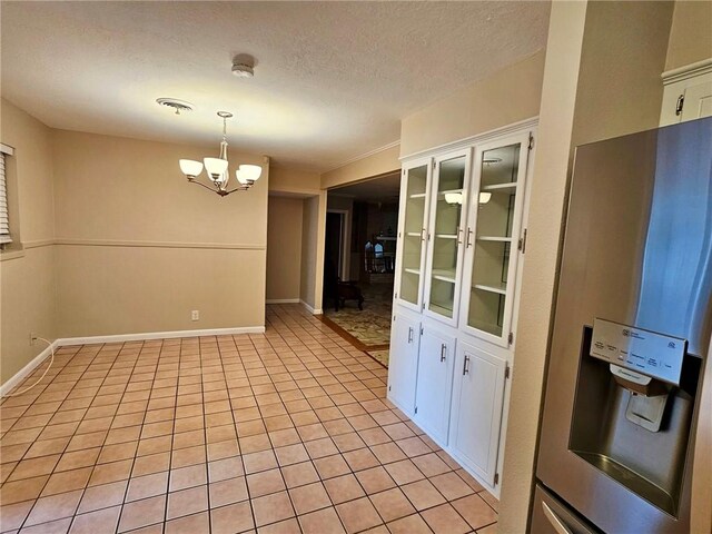 4725 Shea Pkwy, Corpus Christi, TX 78413 - unfurnished dining area featuring an inviting chandelier, a textured ceiling, baseboards, and light tile patterned flooring