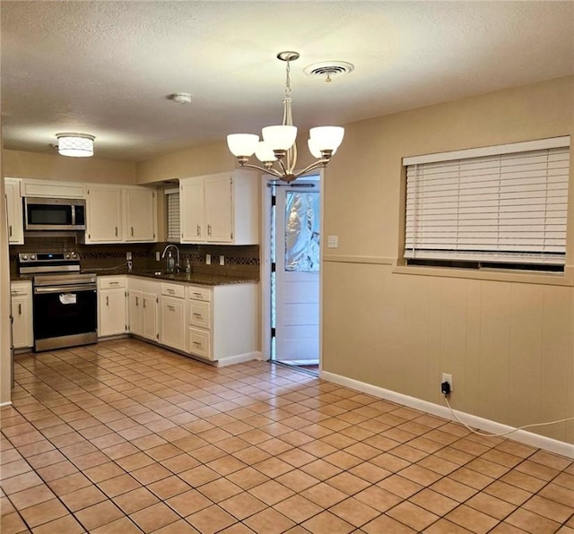 4725 Shea Pkwy, Corpus Christi, TX 78413 - kitchen with a sink, dark countertops, a notable chandelier, white cabinetry, and appliances with stainless steel finishes