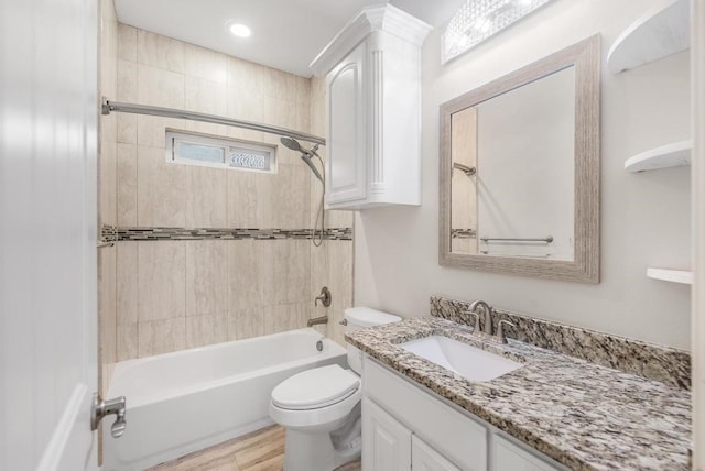 full bathroom with hardwood / wood-style floors, vanity, toilet, and tiled shower / bath