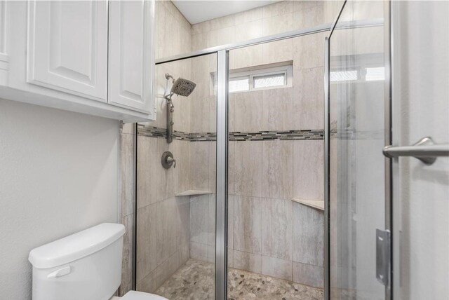 bathroom featuring toilet and a shower with door