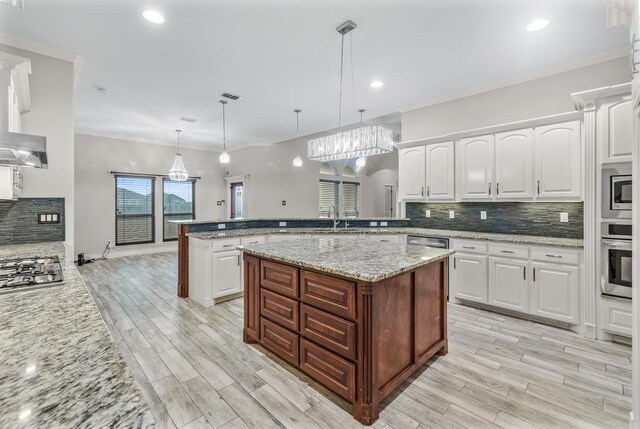 kitchen featuring white cabinetry, stainless steel appliances, light stone counters, kitchen peninsula, and pendant lighting