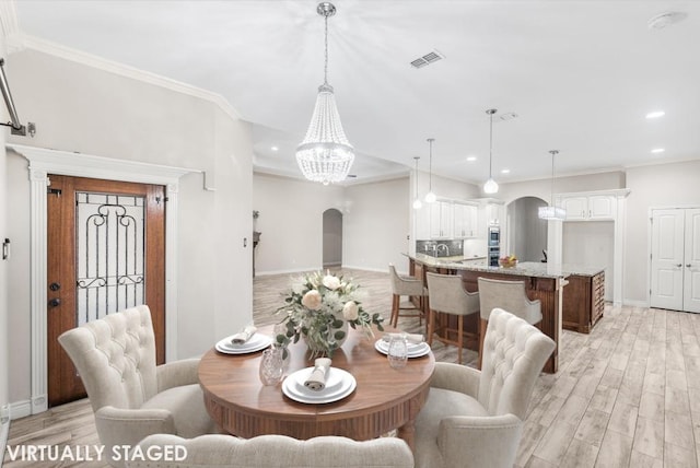 dining room with an inviting chandelier, light hardwood / wood-style floors, and ornamental molding