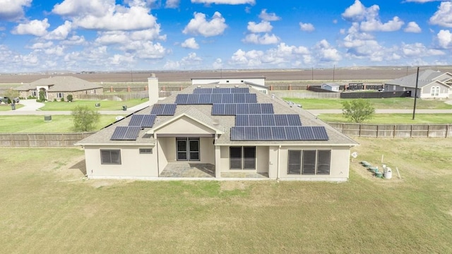 back of property featuring a yard and solar panels