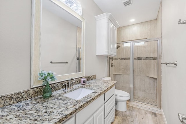 bathroom featuring hardwood / wood-style flooring, vanity, toilet, and a shower with shower door