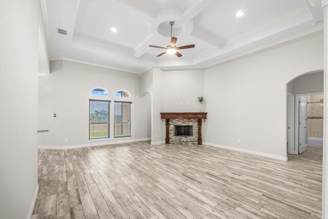 unfurnished living room with ceiling fan, coffered ceiling, crown molding, a fireplace, and light wood-type flooring