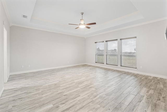 spare room with a raised ceiling, crown molding, light hardwood / wood-style flooring, and ceiling fan