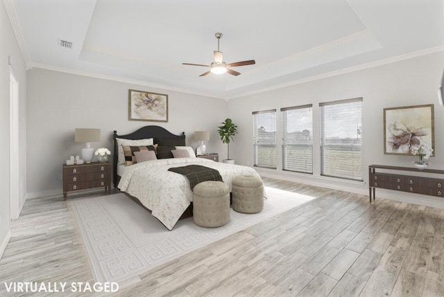 bedroom featuring a tray ceiling, ceiling fan, ornamental molding, and light wood-type flooring