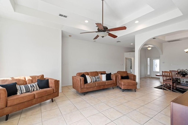 living room with visible vents, a raised ceiling, arched walkways, and recessed lighting