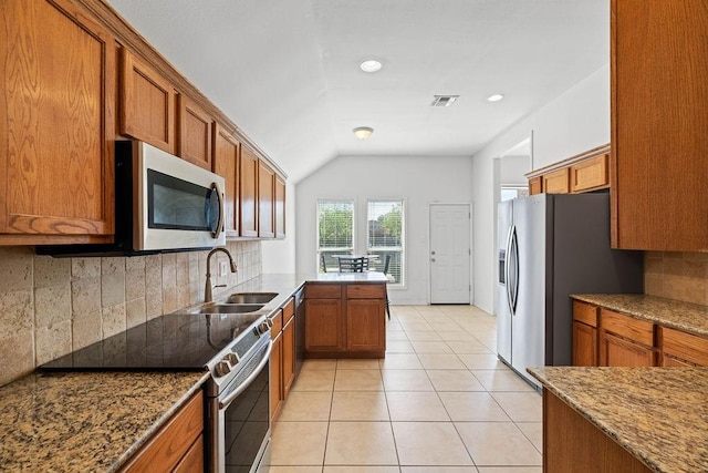 kitchen featuring brown cabinetry, a sink, stainless steel appliances, and decorative backsplash