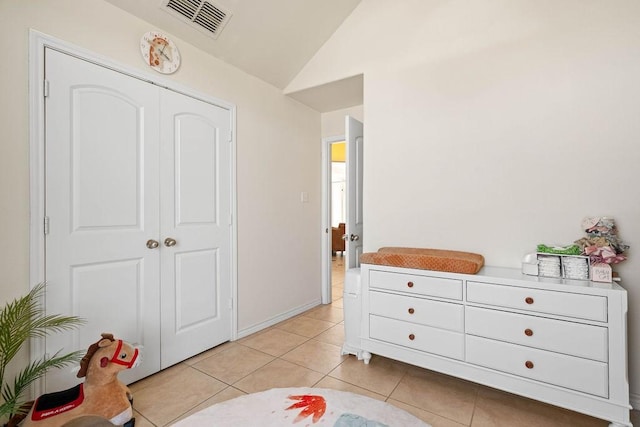 bedroom with visible vents, light tile patterned flooring, a closet, and vaulted ceiling
