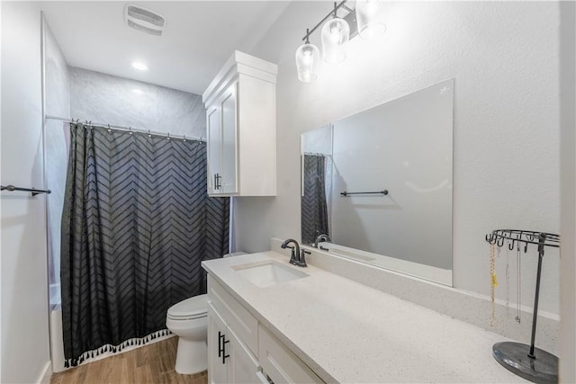 full bath featuring visible vents, toilet, wood finished floors, recessed lighting, and vanity