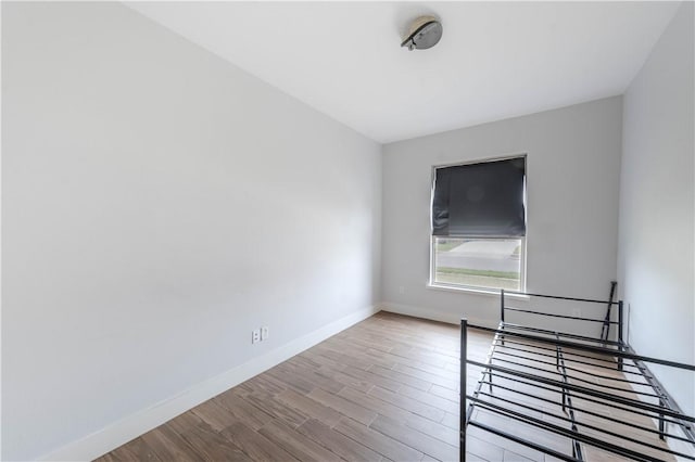 spare room with baseboards and wood finished floors