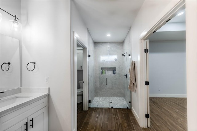 full bath with vanity, wood finished floors, baseboards, a stall shower, and toilet