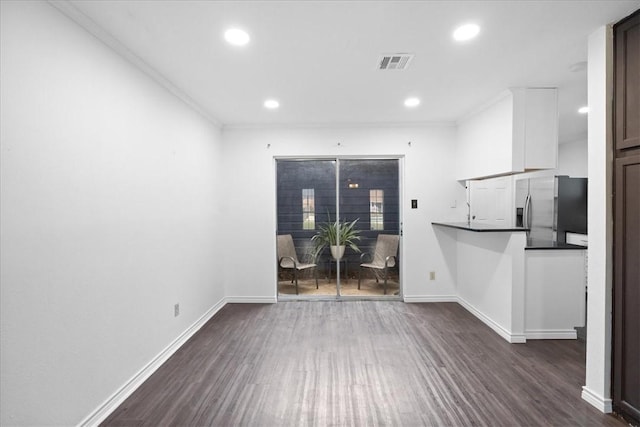 unfurnished living room featuring dark hardwood / wood-style flooring and crown molding